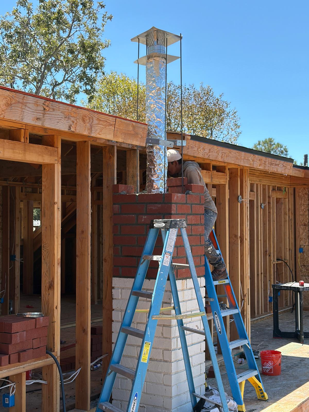 Brick masonry work in progress around a chimney flue