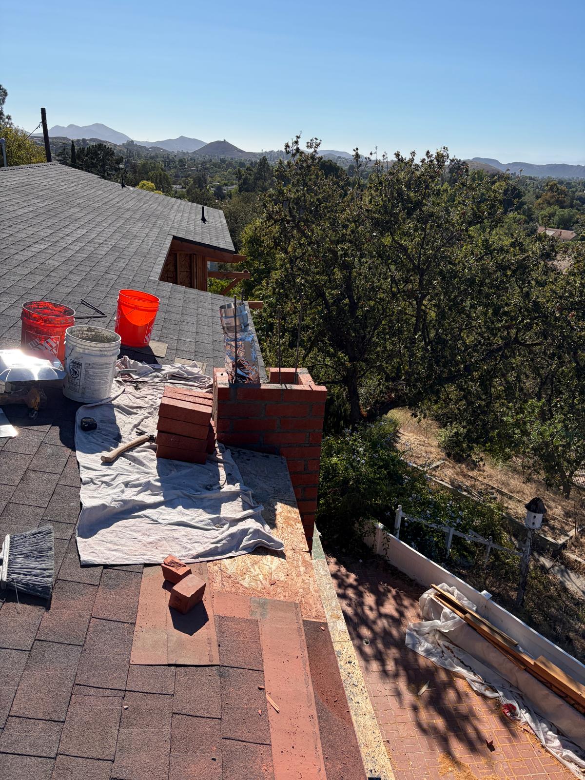 Rooftop chimney work area with tools and protective coverings